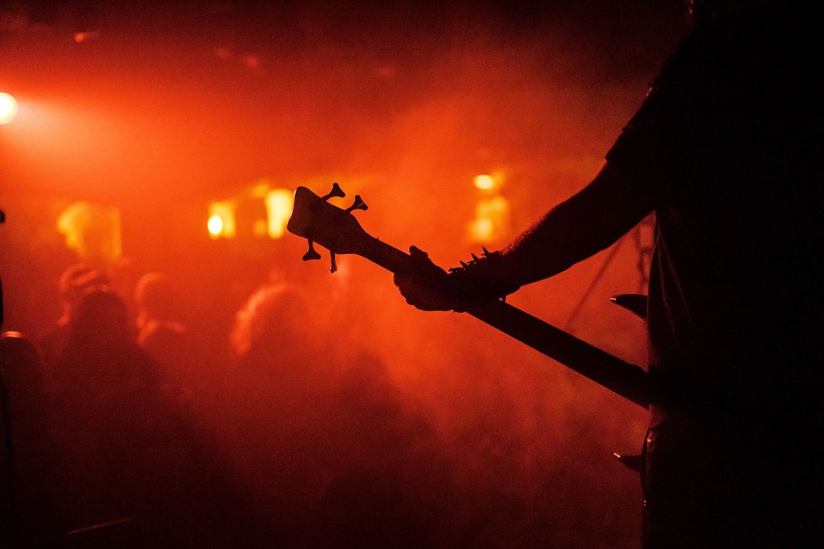 Silhouette of a musician holding a bass guitar at a metal concert.