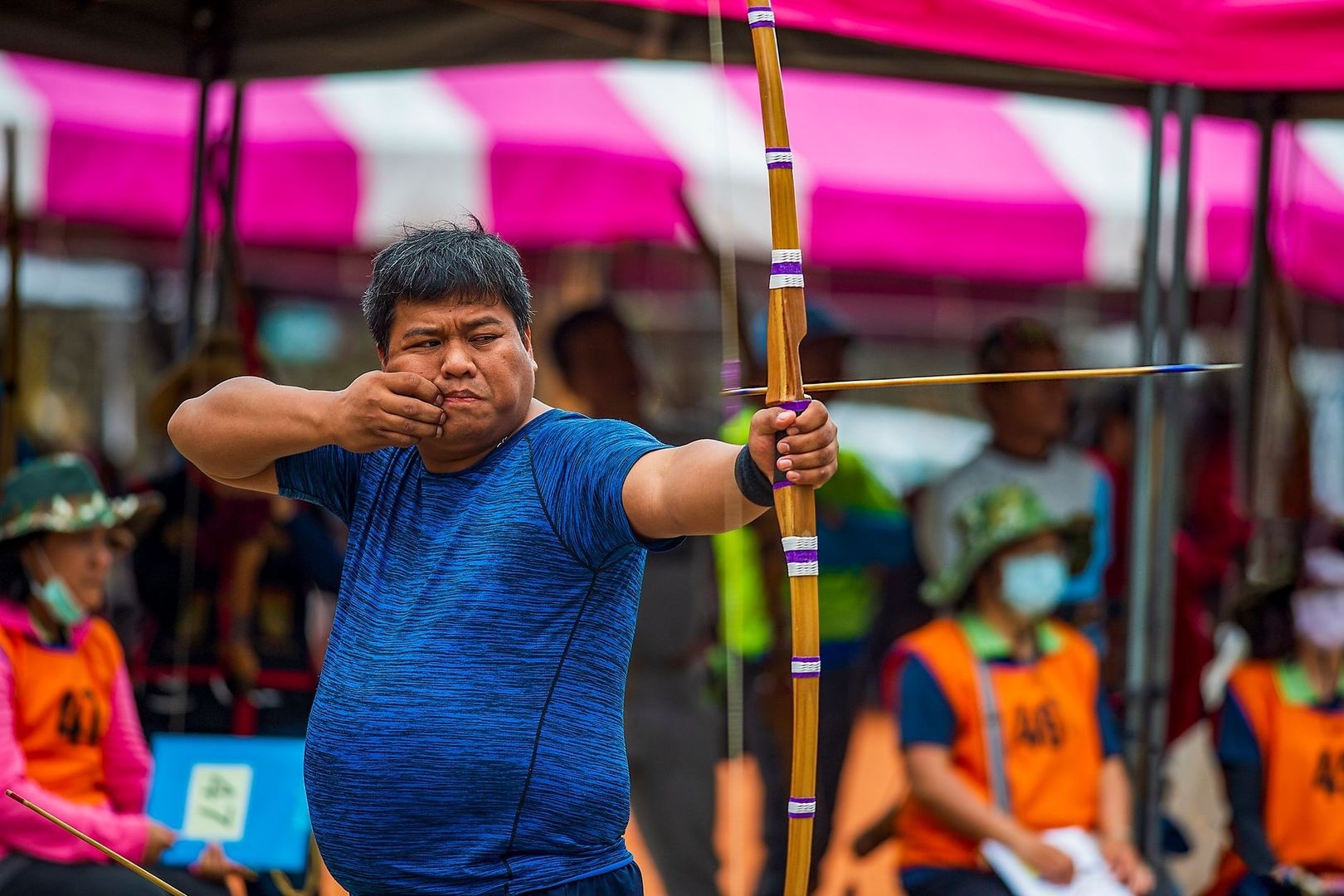 Archer drawing a traditional bow while aiming at a target